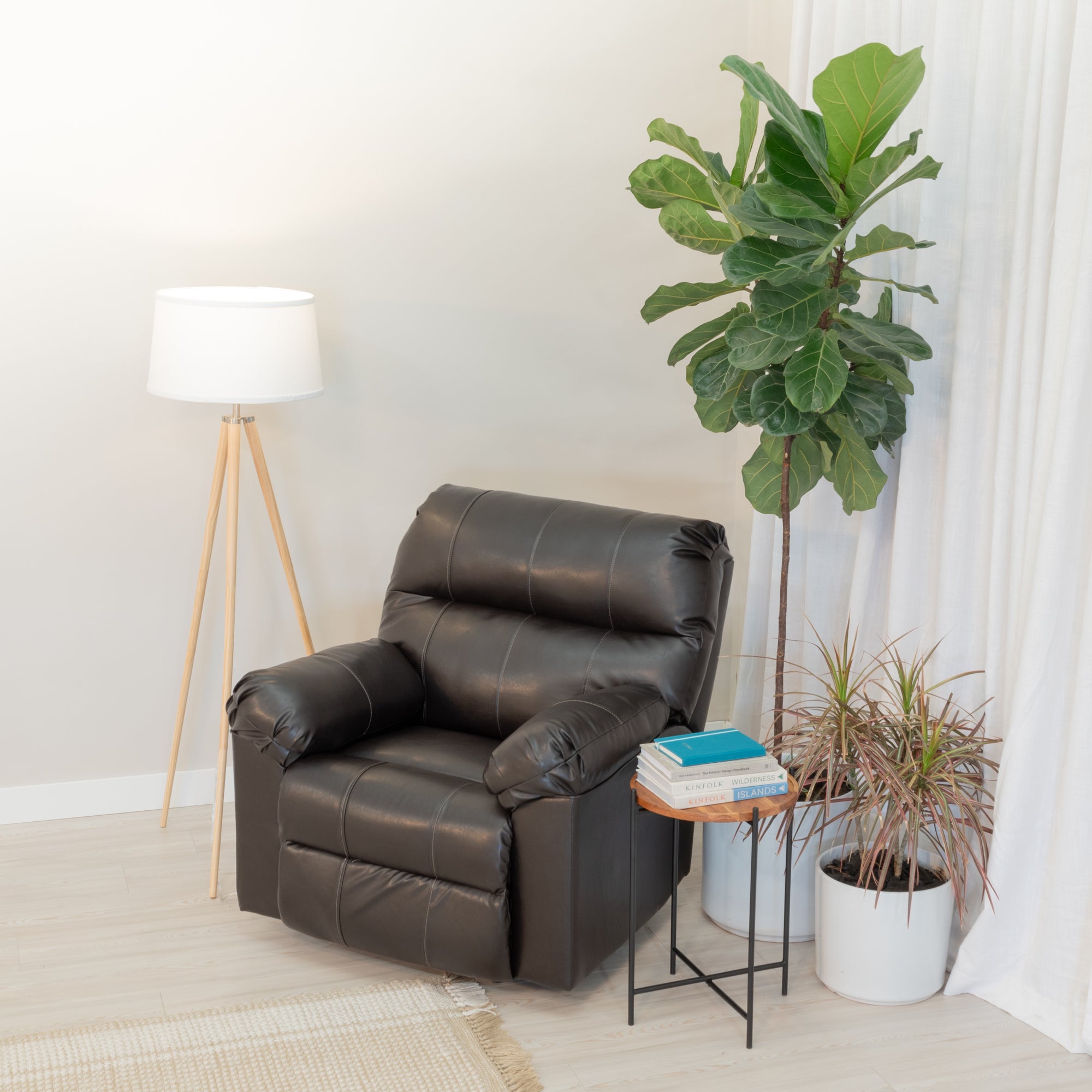 An overstuffed recliner sits in a comfortable looking living room. it is surrounded by house plants, a side table and lamp.