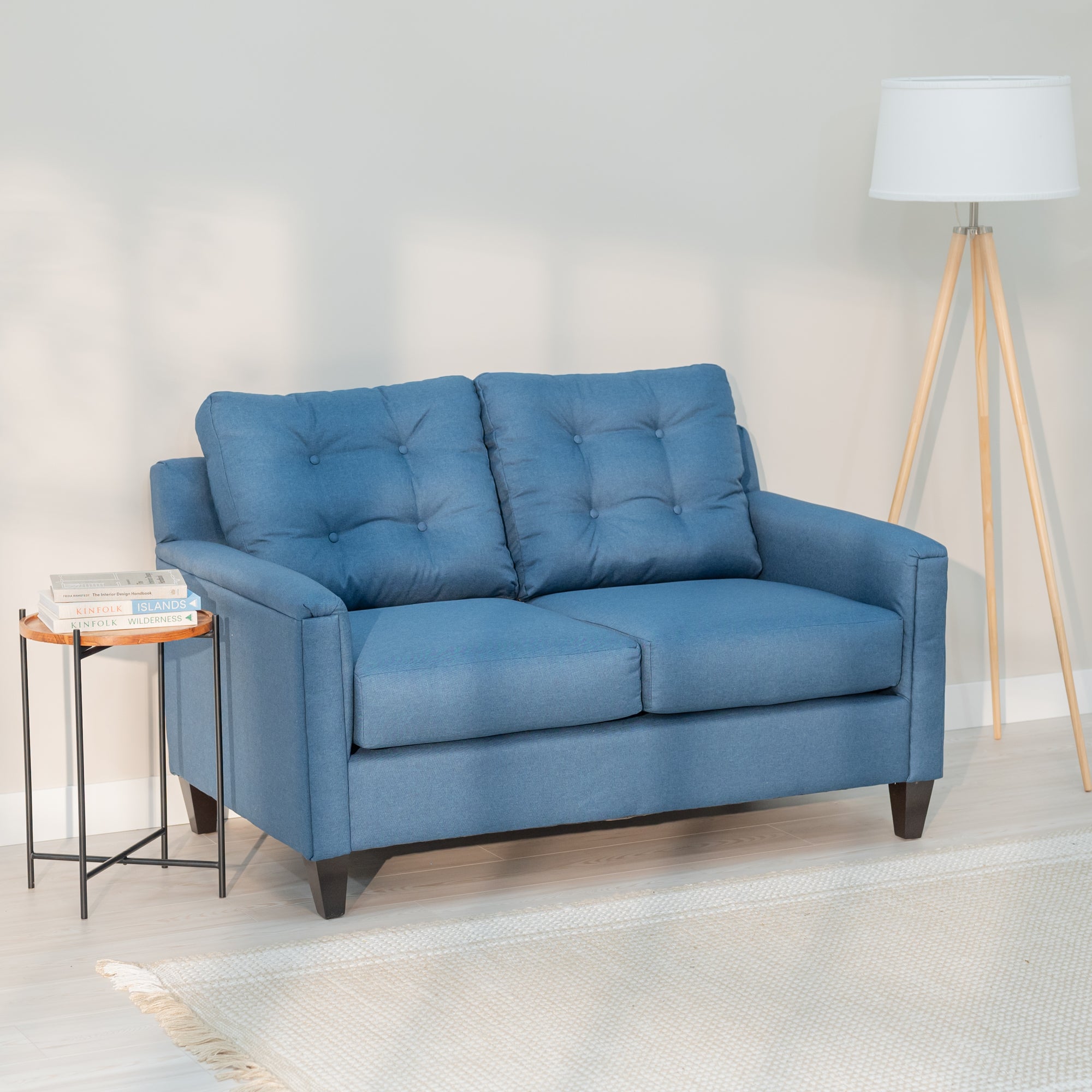 A denim blue love seat and sofa in a nice looking living room. The sofa and loveseat have clean lines, rectangular arms and a tufted back.