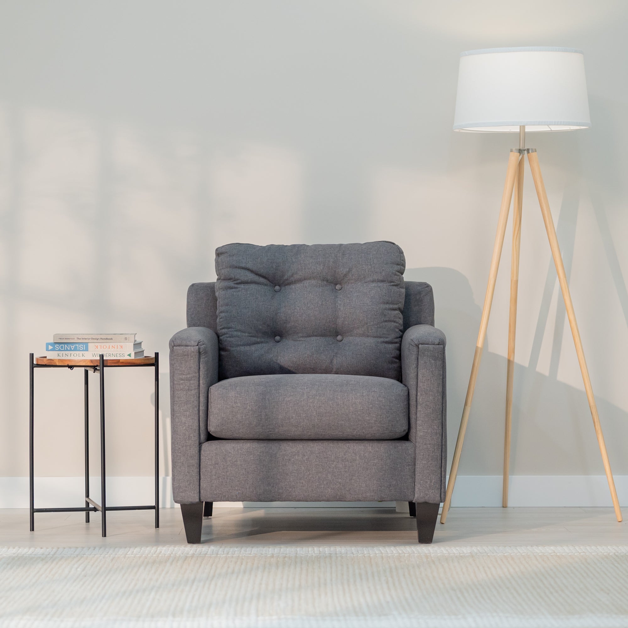 A front view of the grey chair showing it modern rectangular shape and plush looking tufted back.