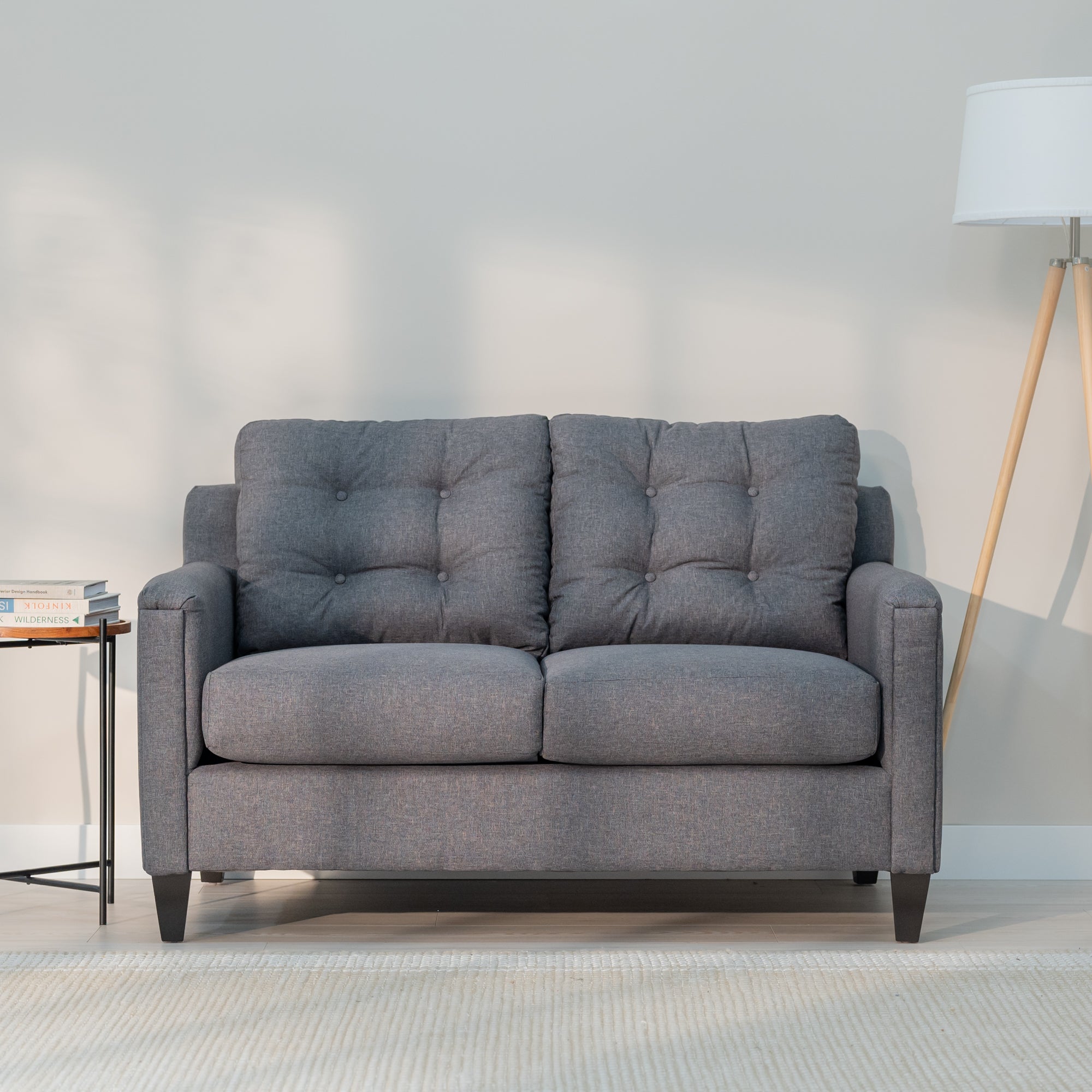 A front view of the grey loveseat showing it modern rectangular shape and plush looking tufted back.