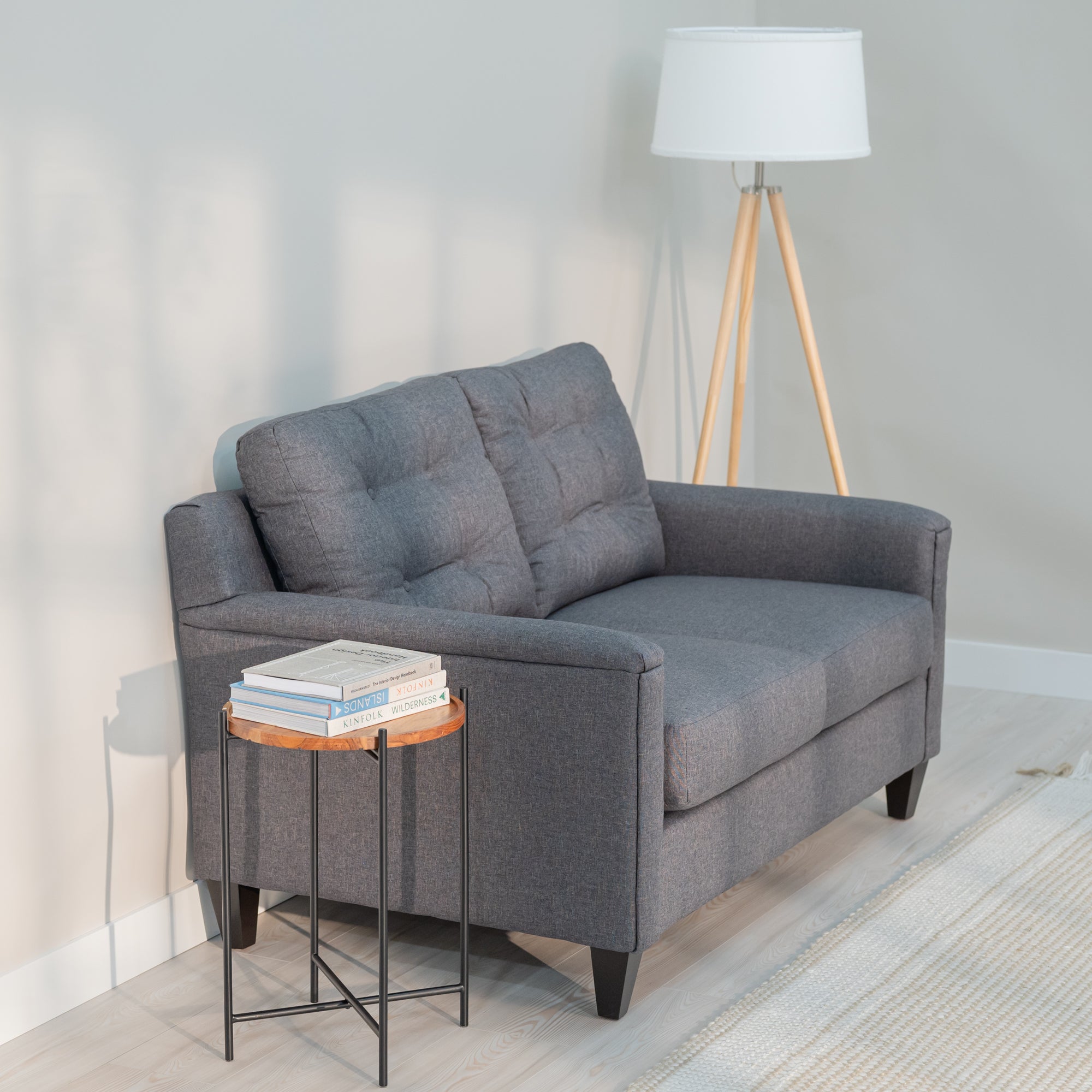 A side view of a grey  love seat and sofa in a nice looking living room. The sofa and loveseat have clean lines, rectangular arms and a tufted back. the side view shows a gently angled back for a comfortable siting position