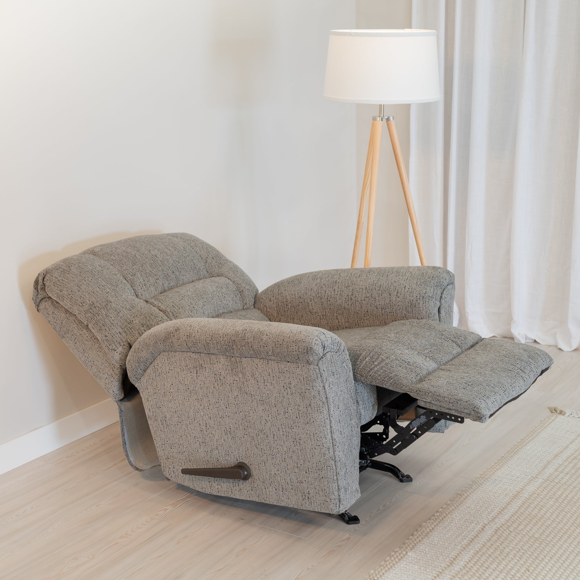 the recliner is shown with its foot rest extended, and back reclined, demonstrating its ability to lay provide a nearly flat laying surface.