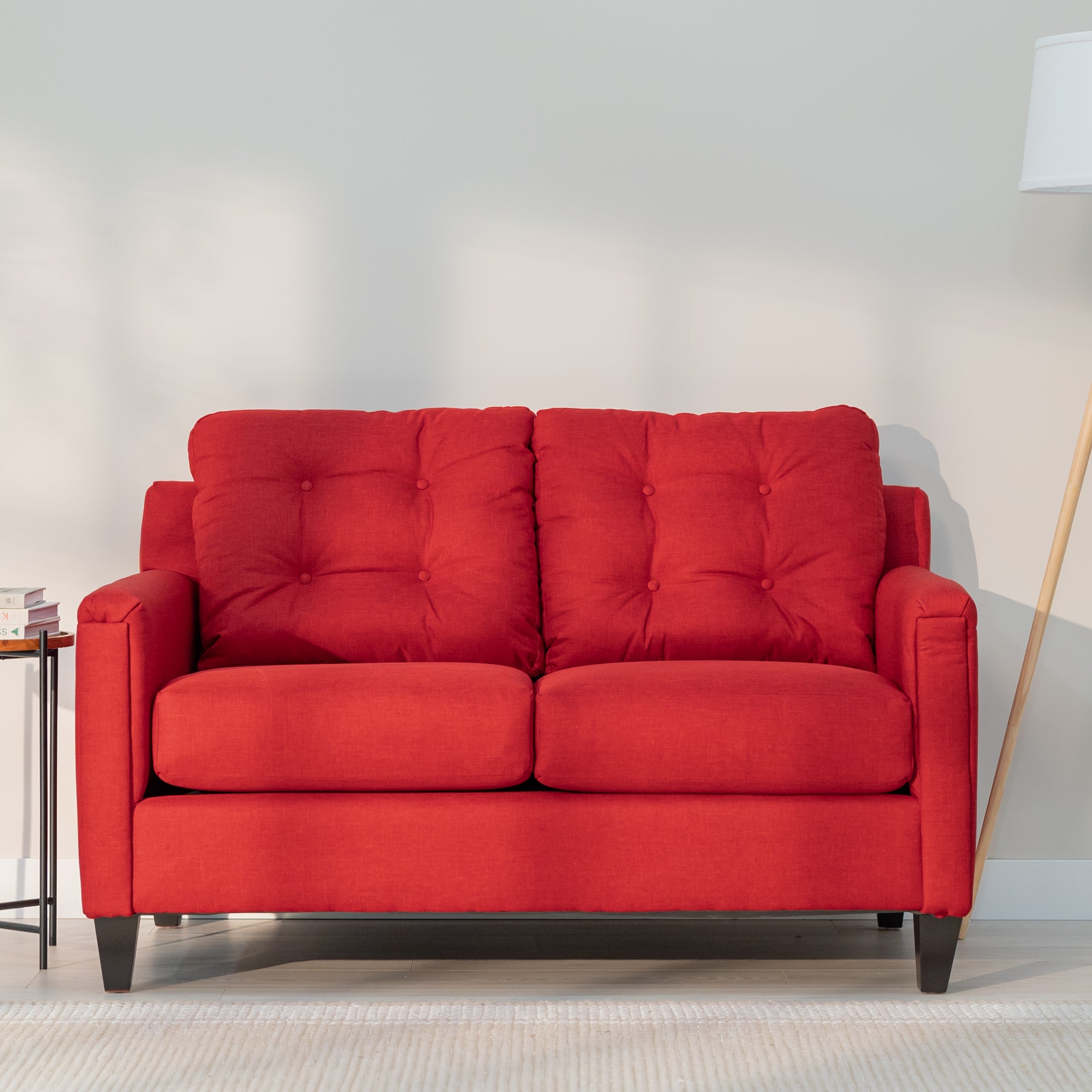 A front view of the red loveseat showing its modern rectangular shape and plush looking tufted back.