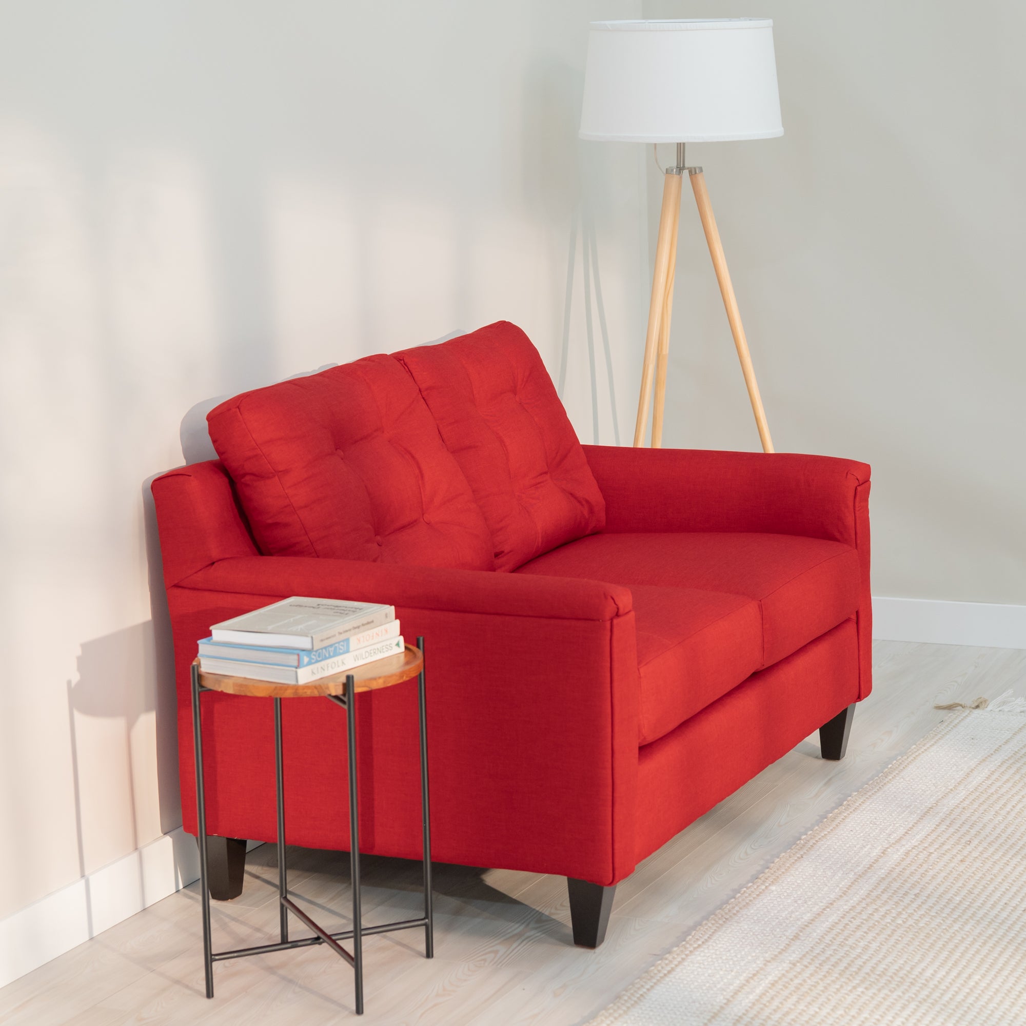 an angled view of the red loveseat showing its modern rectangular shape and plush looking tufted back, sloping back and a comfortable angle